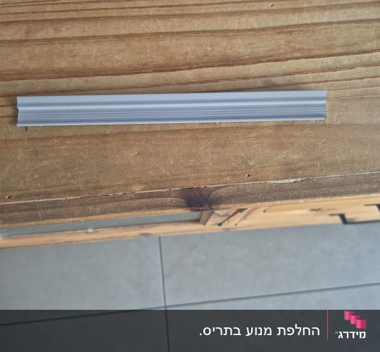 פרופיל מתכת על שולחן עץ עם רצפת אריחים